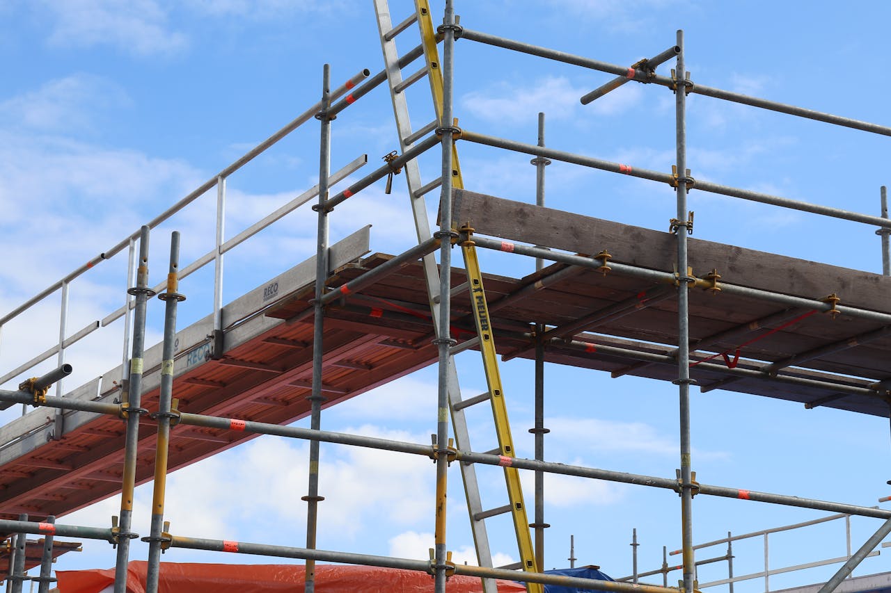 Detailed view of a construction site scaffolding structure and ladder against a bright blue sky.