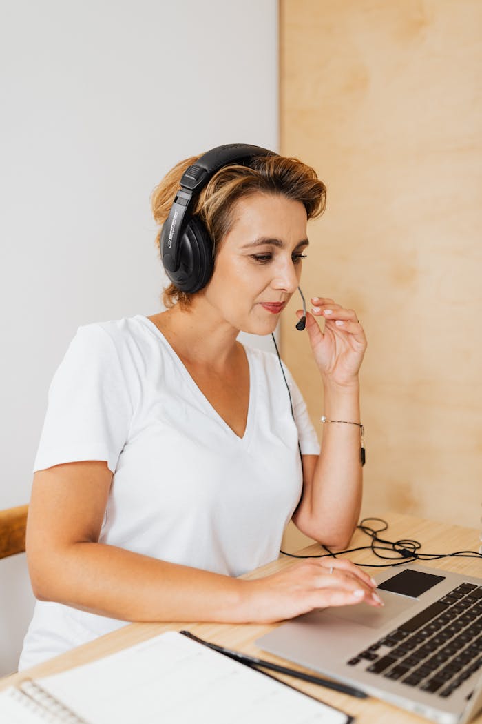Professional woman using a laptop and headset for remote work, engaged in video conferencing